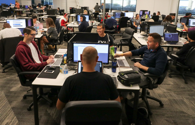 A group of students working on their laptops in a modern classroom, symbolizing the intensive learning environment of a coding bootcamp.
