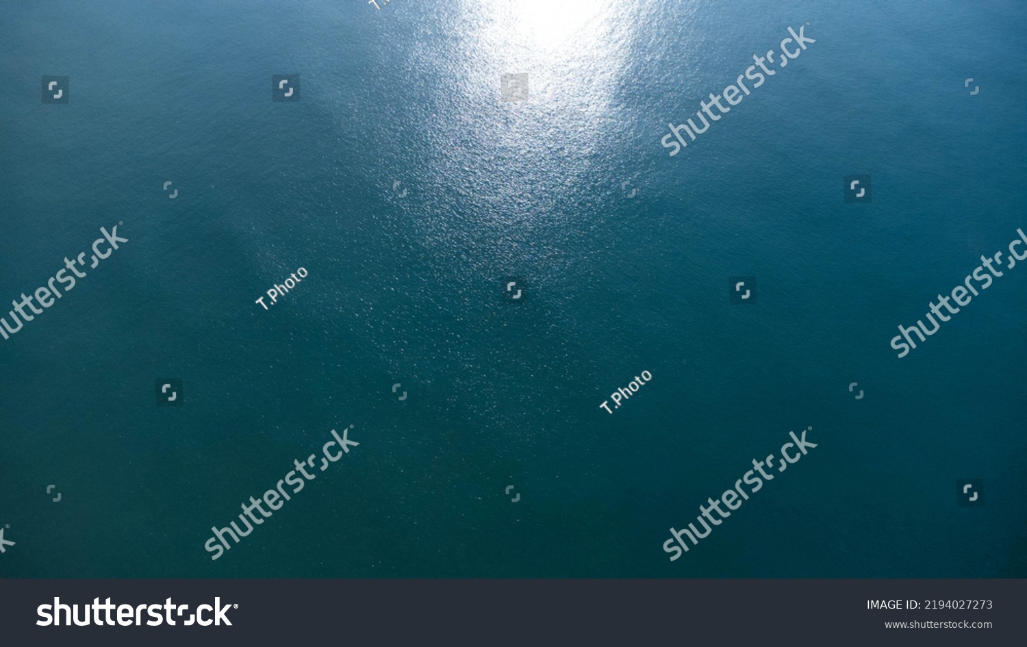 Aerial view of the sea with sunlight reflecting on the surface, captured by drone.